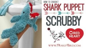 An instructional image showing a blue crochet shark washcloth puppet on a person's hand, with text describing it as a free pattern and a graphic banner promoting the website MarlyBird.com. -Marly Bird