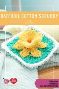 A promotional image featuring a yellow daffodil-shaped cotton washcloth on top of a stack of folded towels, with a video tutorial title and a link for a free pattern. -Marly Bird