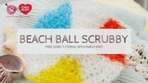 Colorful crocheted beach ball scrubbies surrounded by a shell and cozy yarn, with a label promoting a free Beach Ball Crochet Pattern video tutorial by Marly Bird. -Marly Bird