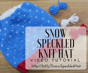 A handmade knit hat with blue and white speckled pattern lies on a wooden surface, accompanied by yarn balls in blue, white, and red. Text overlay says "Snow Speckled Knit Hat" with a URL. -Marly Bird