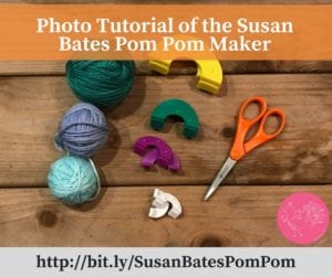 A crafting tutorial image showing a Susan Bates Pom Pom Maker, colorful yarn balls, scissors, and various pom pom maker parts arranged on a wooden table. -Marly Bird