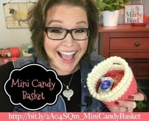 A cheerful woman with glasses holds a mini candy basket containing a chocolate bar. Text bubbles promote a mini candy basket, with a URL link below. -Marly Bird