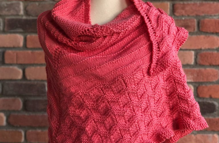 Coral-pink crocheted shawl with textured stitch detail draped on a mannequin, "Social Knitter Shawl" text above.