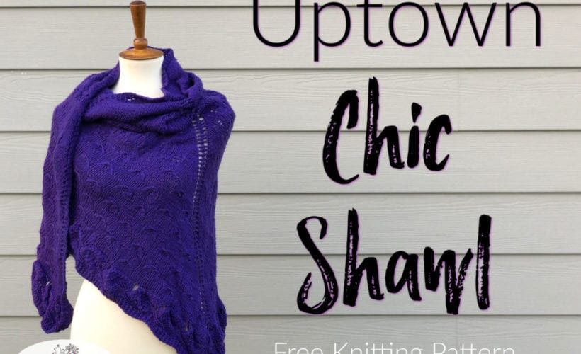 Purple knitted shawl with textured stitches draped on a dress form against a gray wooden wall; Uptown Chic Shawl knitting project.