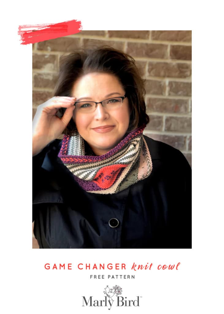 Colorful knit cowl with bold patterns and textured stitches, shown worn by a woman against a brick wall. Game Changer Knit Cowl.
