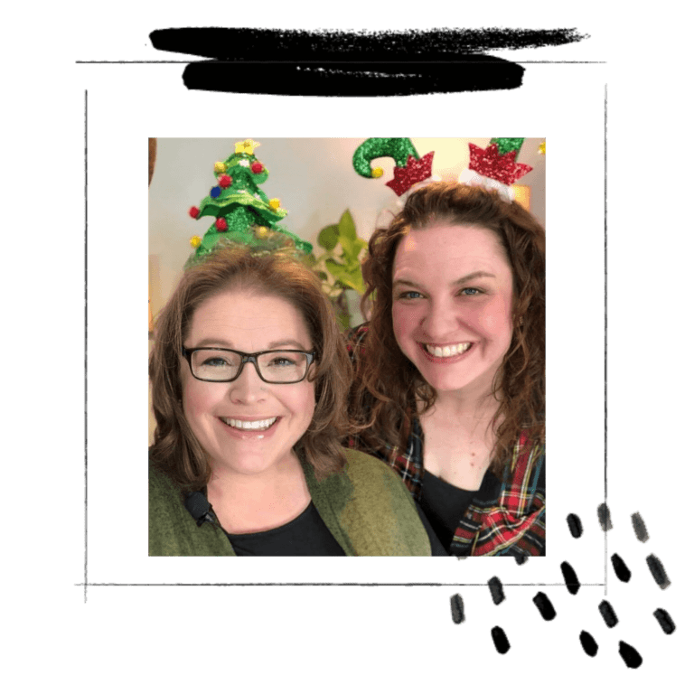 Two women smiling for a photo, one wearing glasses and a green jacket, the other with reindeer antler headband and showcasing Marly Bird knit patterns. Both stand in front of a Christmas tree. -Marly Bird