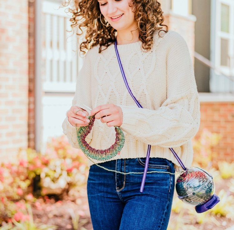 image of woman walking and knitting while wearing a prym yarn-it crossbody.