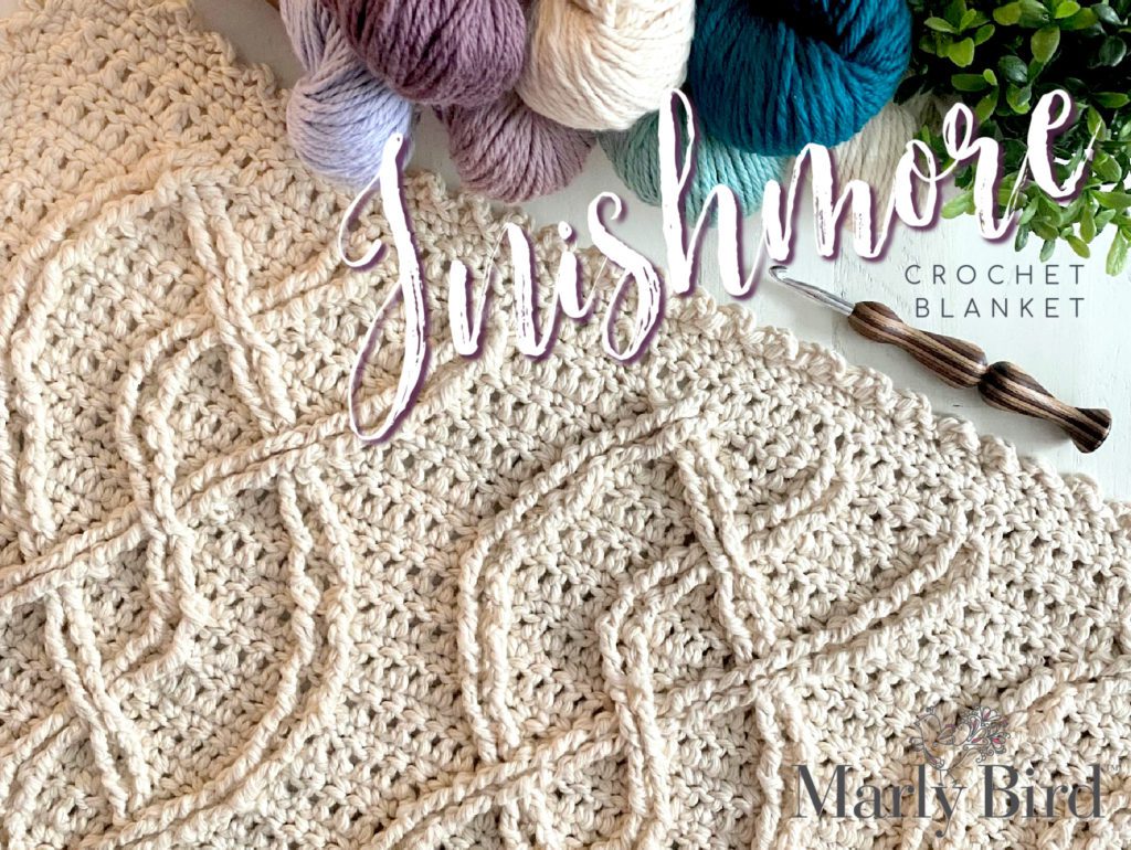 A crochet project in progress with a beautiful textured pattern, surrounded by skeins of colorful yarn and crochet tools, evoking a sense of creativity and craftsmanship for a unique handmade gift. Inishmore Crochet Cable Blanket - Marly Bird