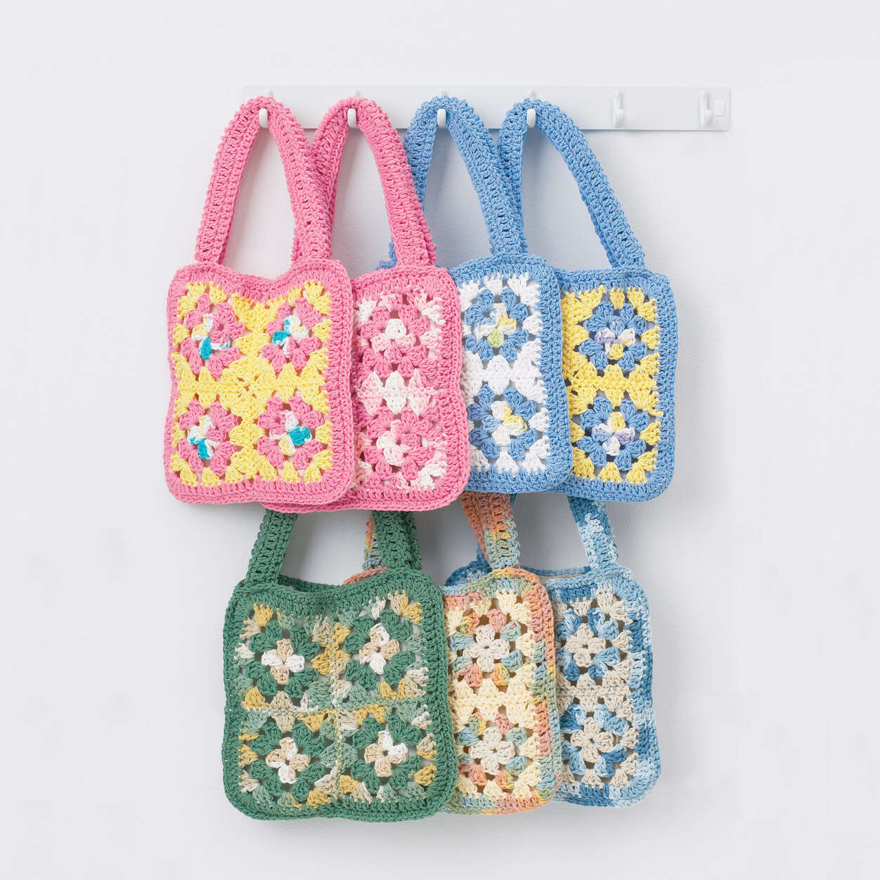 7 Granny Square bags made of 4 multi color squared each side hanging from a coat rack - Marly Bird