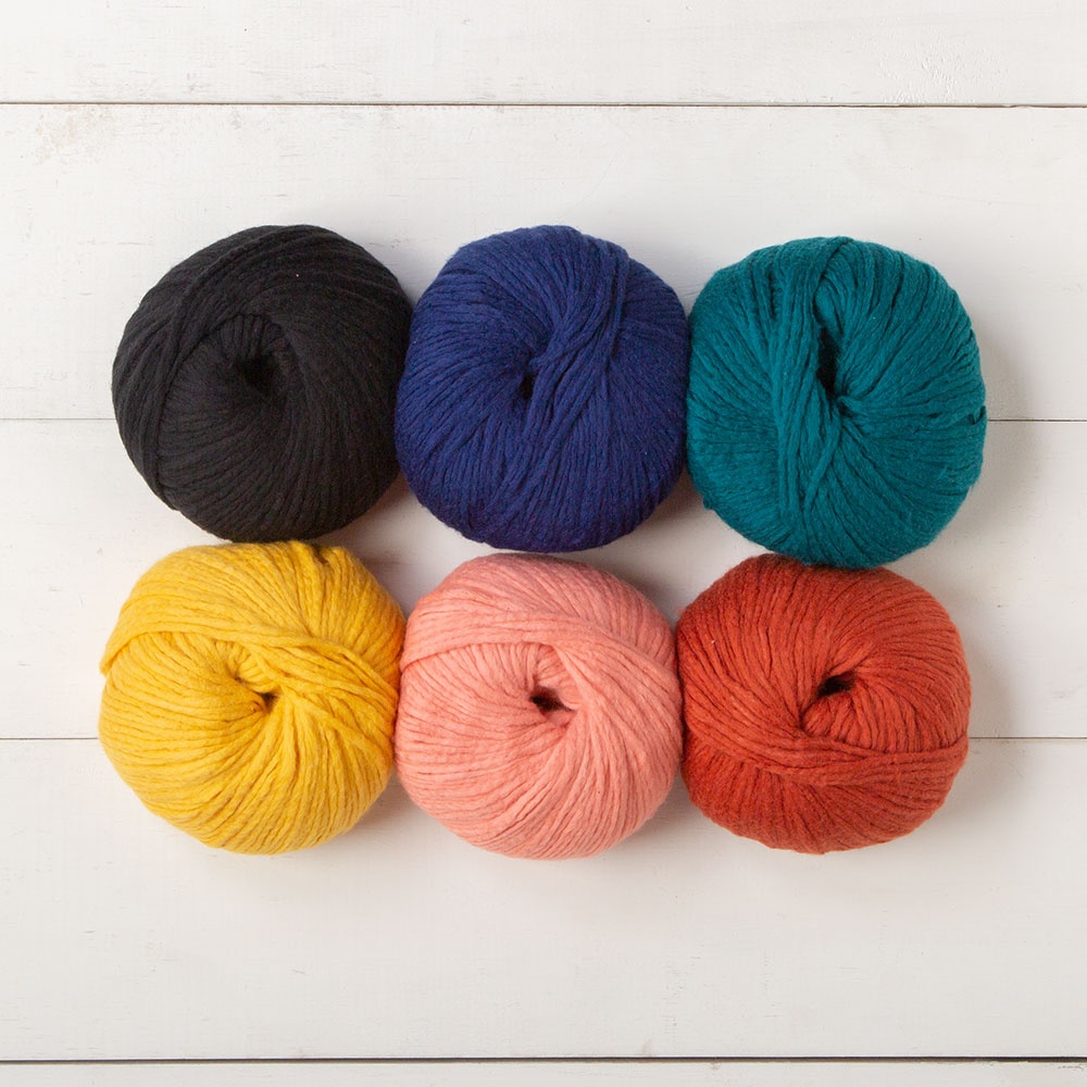 6 shades of WeCrochet Snugglepuff yarn: black, royal, teal, yellow, peach, rust.