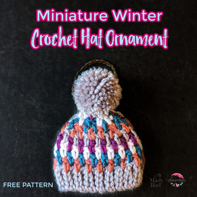 A colorful miniature winter crochet hat ornament with a fluffy pompom on top, displayed against a dark background, with text promoting a free crochet pattern by Marly Bird. -Marly Bird
