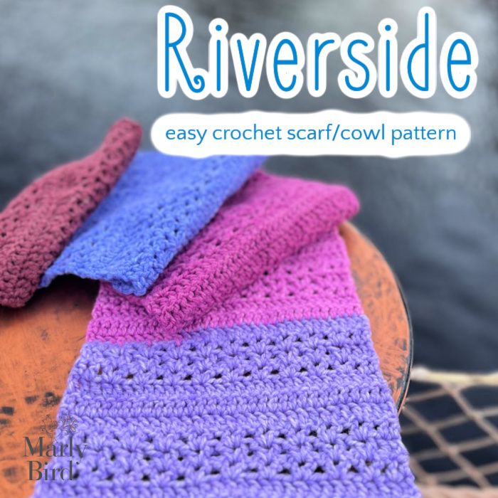 A display of colorful crocheted scarves in shades of pink, blue, and burgundy, labeled "riverside - easy crochet scarf pattern" by Mark Bird. Scarves are draped over a wooden surface. -Marly Bird