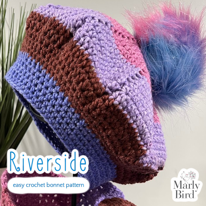 Close up side view of Riverside Bonnet with large blue, pink, purple fur pompom.