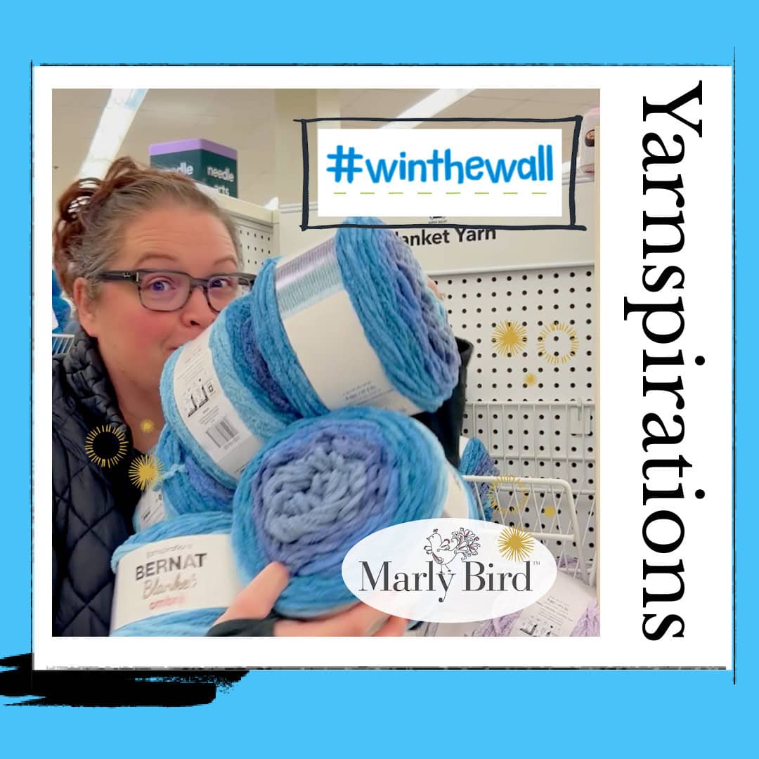 A woman in a store smiling behind stacked yarn balls with promotional signs reading "#winthewall" and "yarnspirations" for a free yarn giveaway. A labeled photo of "Marly Bird" is overlaid. -Marly Bird