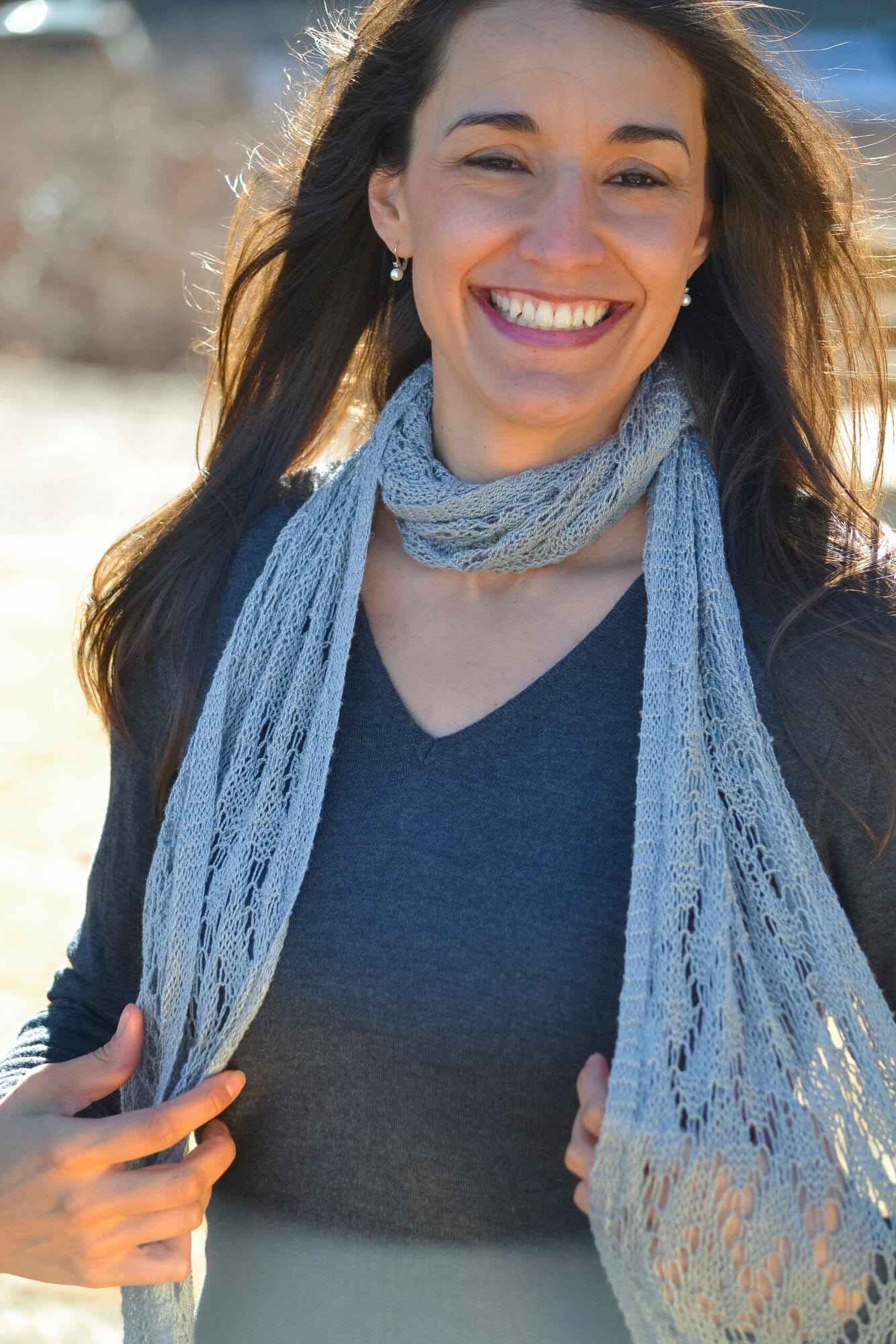 Marly Bird modeling the Shangri-La free knit lace shawl scarf pattern with the full offset lace panel visible.