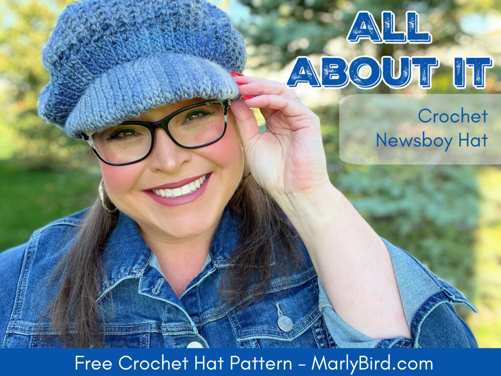 Smiling woman wearing a blue crochet newsboy hat in a park setting with text overlay 'ALL ABOUT IT - Crochet Newsboy Hat - Free Crochet Hat Pattern - MarlyBird.com'.