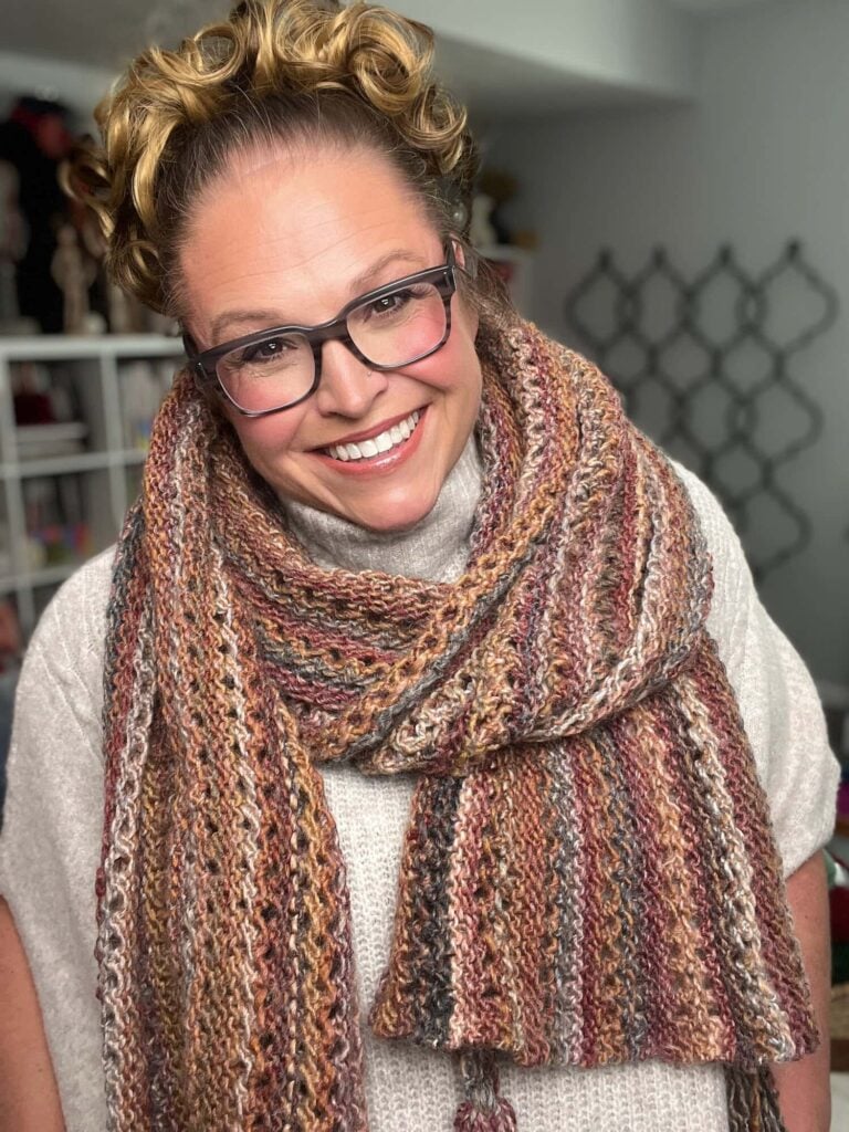 Almond Brittle free knit lace wrap in bulky weight yarn, draped to show the lace band stitch pattern and tassel corners.