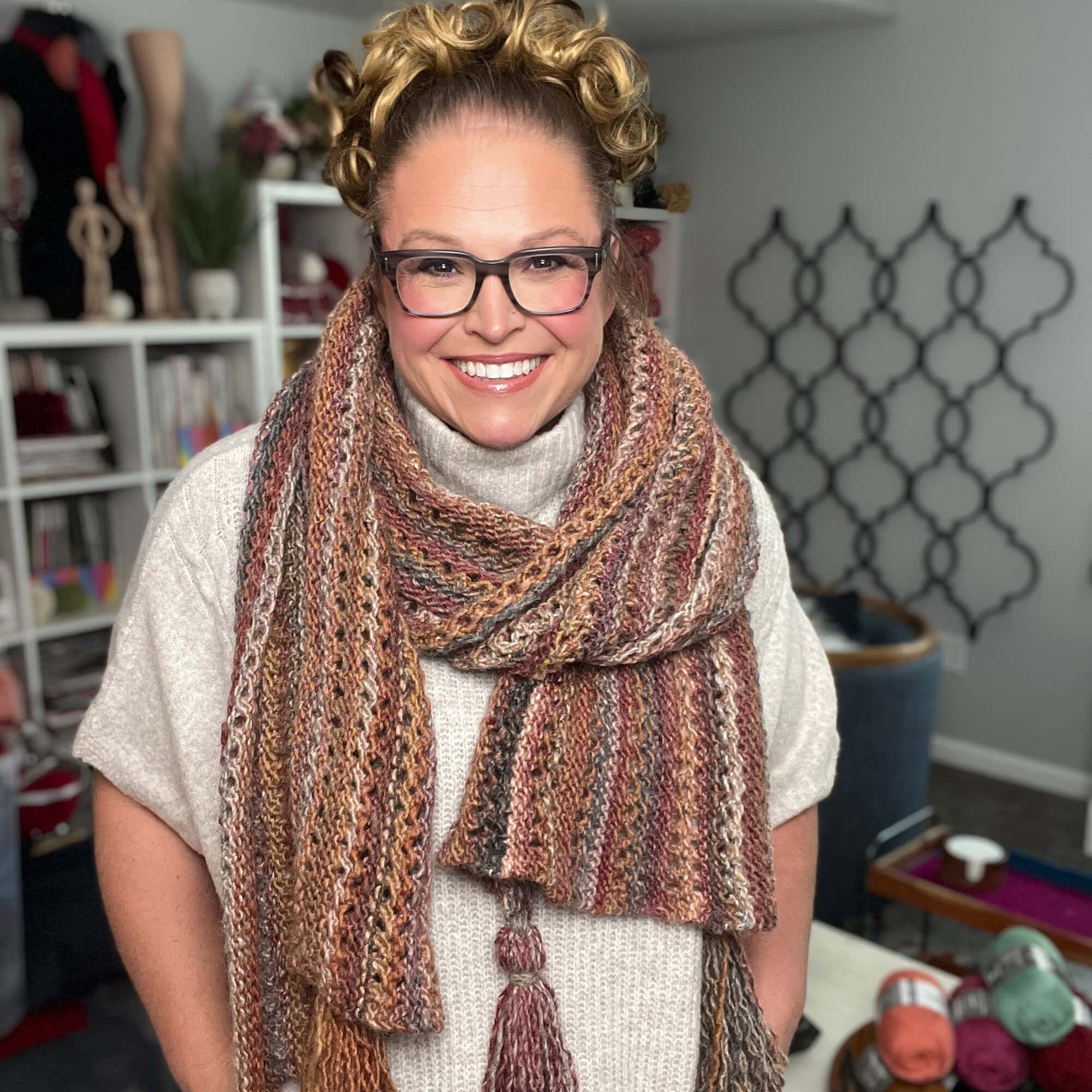 A person models a chunky, multicolored almond brittle knit wrap, highlighting the cozy texture and color transitions.