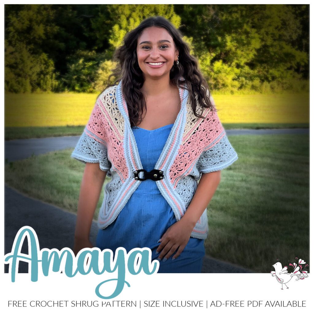 A person wearing a colorful crochet shrug and a blue dress smiles while standing outdoors on a grassy background. Text below reads "Amaya," highlighting the availability of a free crochet shrug pattern and PDF. -Marly Bird