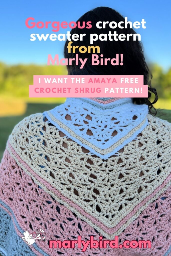 The image features a person draped in a triangular crochet shawl with cream, pink, and blue sections. Text overlays label it as an Amaya Crochet Pattern from Marly Bird and mention the free Amaya Stylish Shrug pattern. The background offers a glimpse of a blurred landscape. -Marly Bird