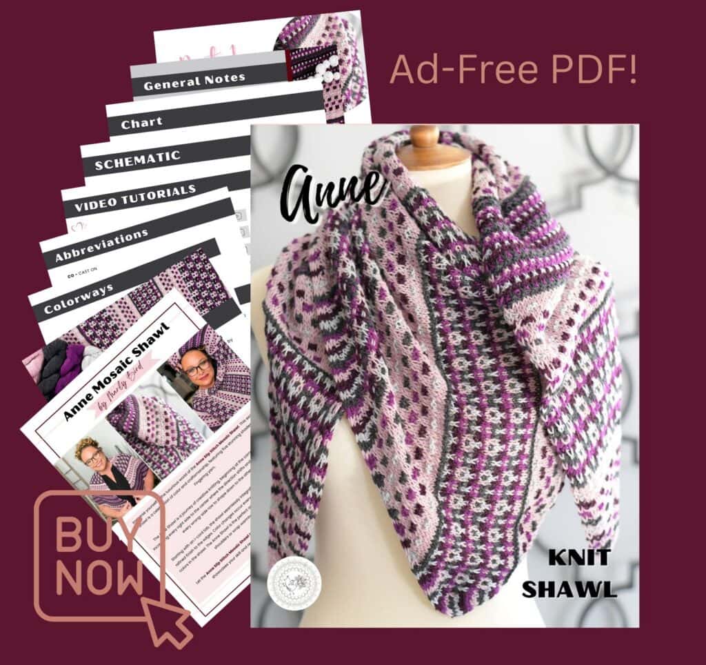 A pink, purple, and white knit mosaic triangle shawl draped on a mannequin with printed pattern sheets beside it.