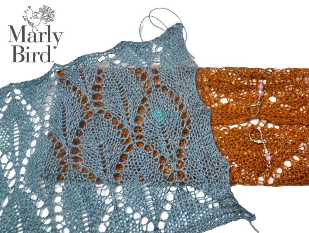Blue and orange lace-knit swatches are shown side by side on a white background. The Marly Bird logo appears in the top left corner, highlighting free knitting and crochet patterns. Two stitch markers are attached to the orange swatch. -Marly Bird