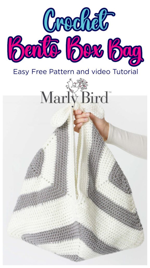 Crochet Bento Box Bag in text, marly bird logo, hand holding a sample of the crochet bag pattern to view. Bag is gray and white - Marly Bird