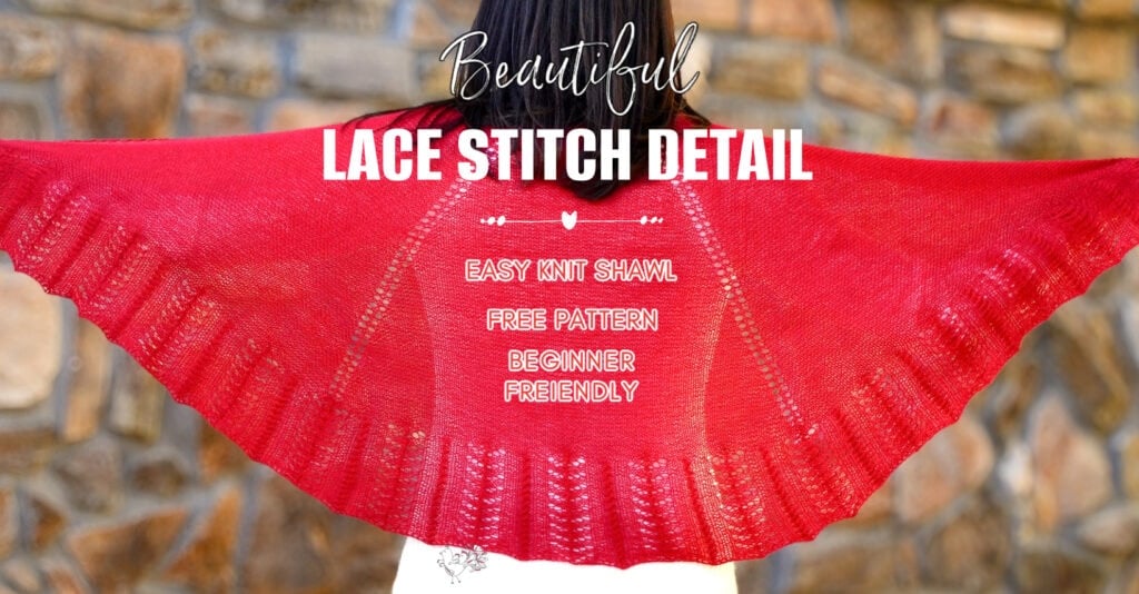 Large red knit shawl with lace stitch detail displayed against a stone wall, showing texture and drape.