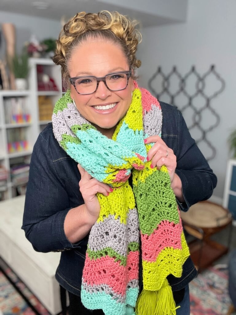 Person displays a striped crochet accessory in green, mint, gray, and pink; distinct textured stitches are visible.