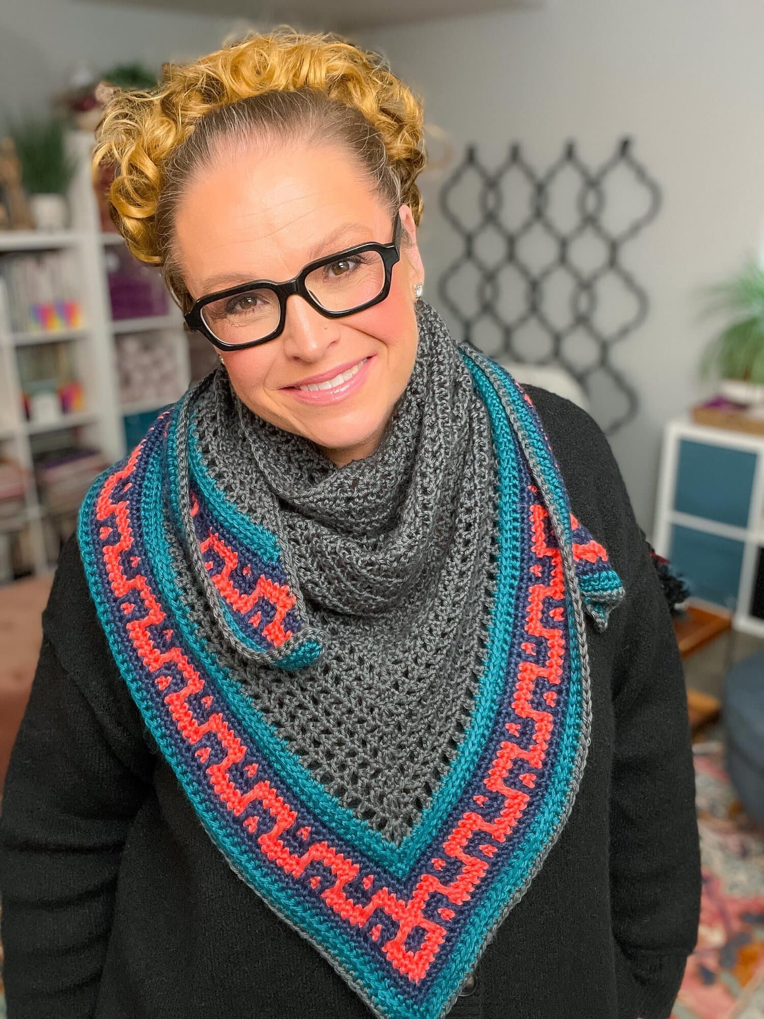 Coral Ridge free crochet triangle shawl draped over the shoulders of a model in a black sweater — colorblock red and teal border frames the collarbone