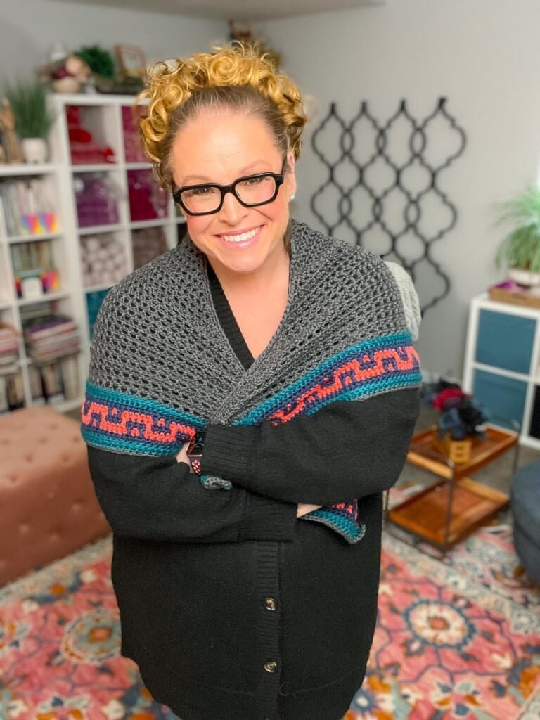 Coral Ridge free crochet triangle shawl — Marly Bird modeling the gray crochet shawl with colorwork border in her colorful craft room