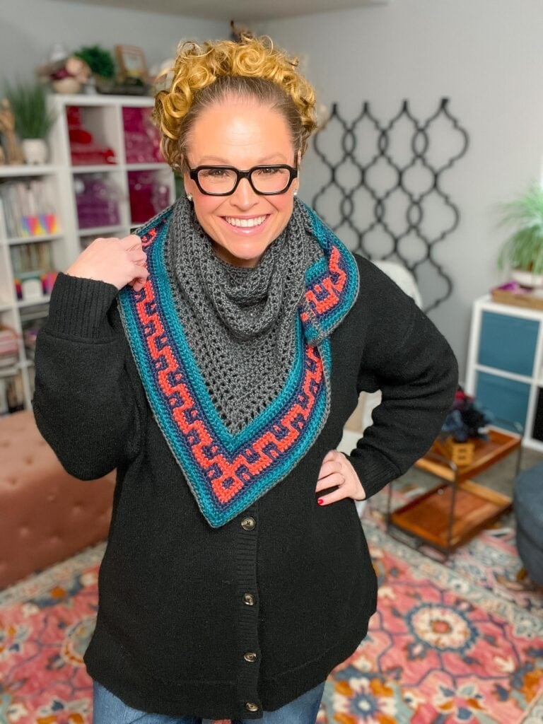 Handmade crochet shawl styled as a crochet scarf wrap — Coral Ridge worsted weight crochet shawl in gray and teal with colorblock Greek-key border, layered over a black cardigan