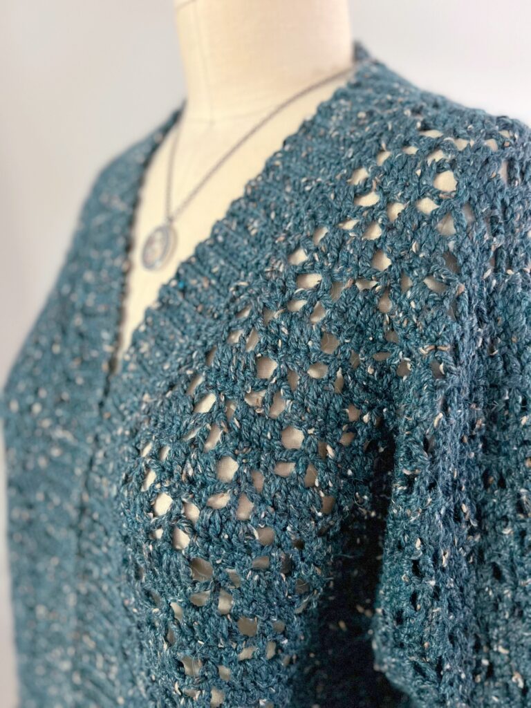 Aurora Lace Crochet Cardigan on a mannequin showing the side view of the left front and partial sleeve of the crochet sweater by Marly Bird. One piece sweater.