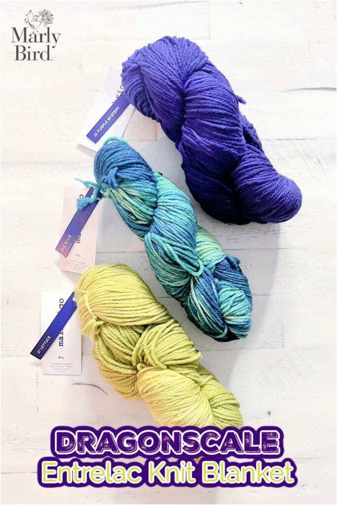 Three skeins of yarn in purple, green-blue, and yellow are arranged vertically on a white wood surface. “Marly Bird” is in the top left corner, and “DRAGONSCALE Entrelac Knit Blanket” highlights this textured knit blanket project. -Marly Bird