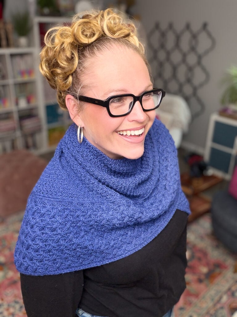 Finished Eowyn cable knit triangle shawl modeled over a black top, showing intricate cable and double moss stitch detail.