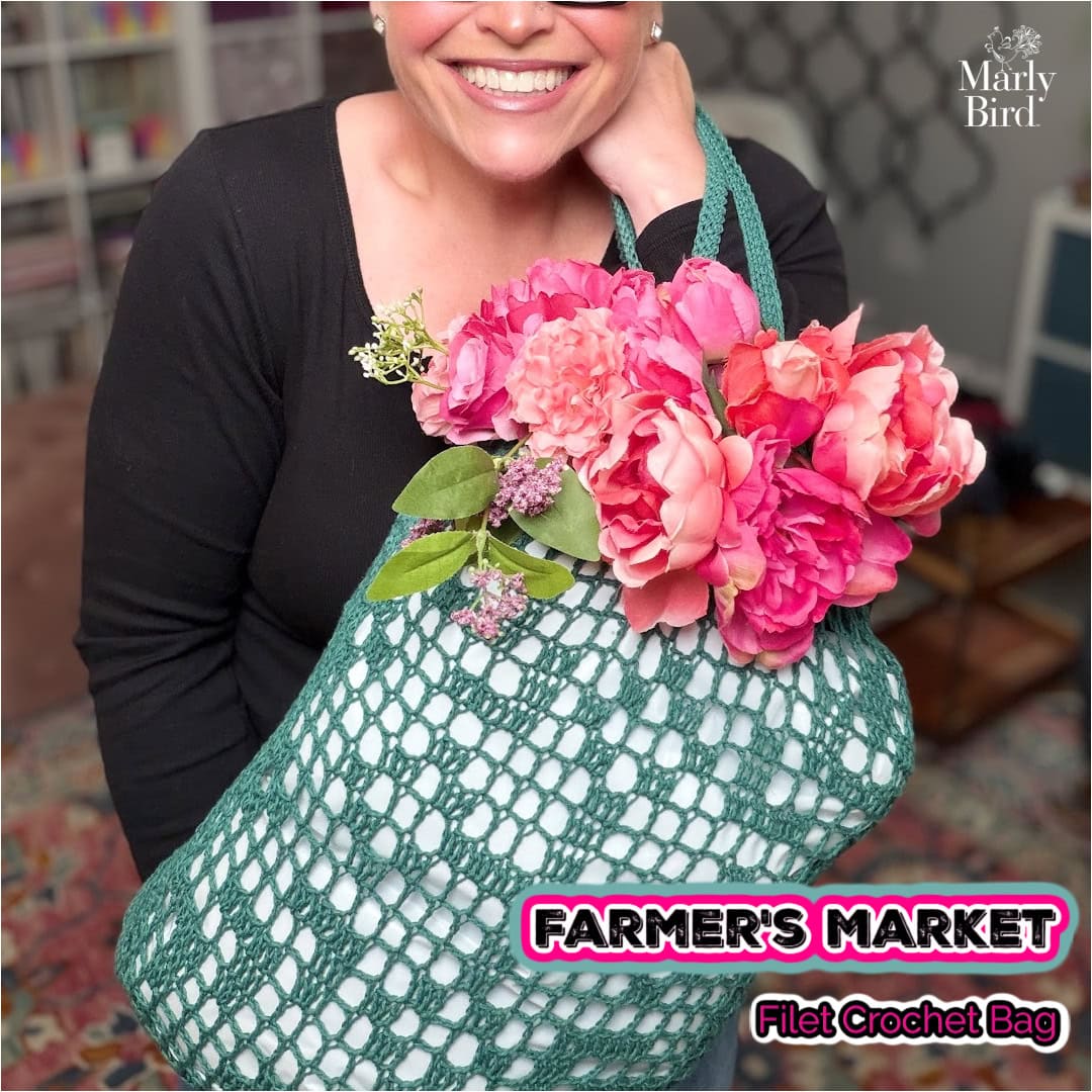 A person displays a green mesh filet crochet bag holding pink flowers, highlighting the openwork stitch and sturdy handles.