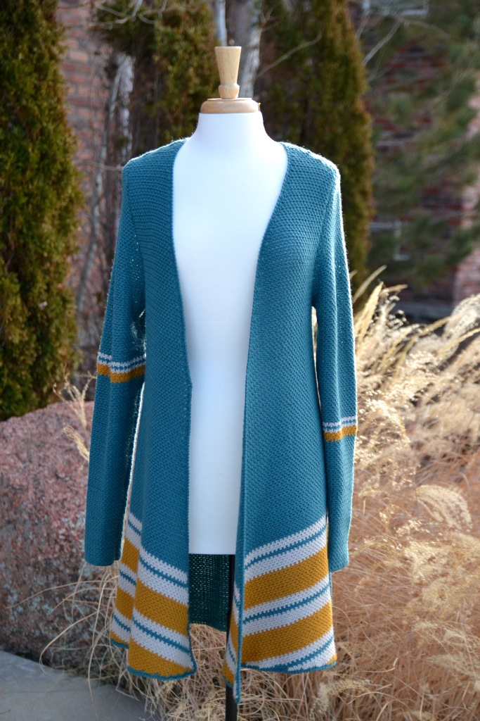 Hamilton Crochet Cardigan shown on a mannequin. The cardigan is made in color teal, cold and off white, long sleeved and drape front - Marly Bird