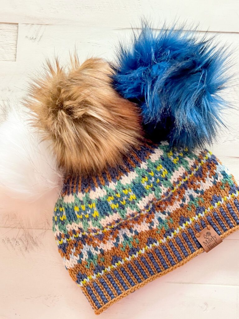 Harmony Hues Hat with three different faux fur pom poms on top to show how different colors work with this pattern - marly bird