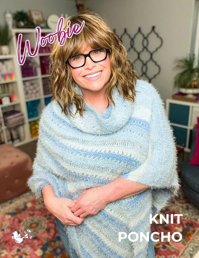 Woman models a light blue knit Woobie Poncho showing textured stitches; yarn and plants in the background.