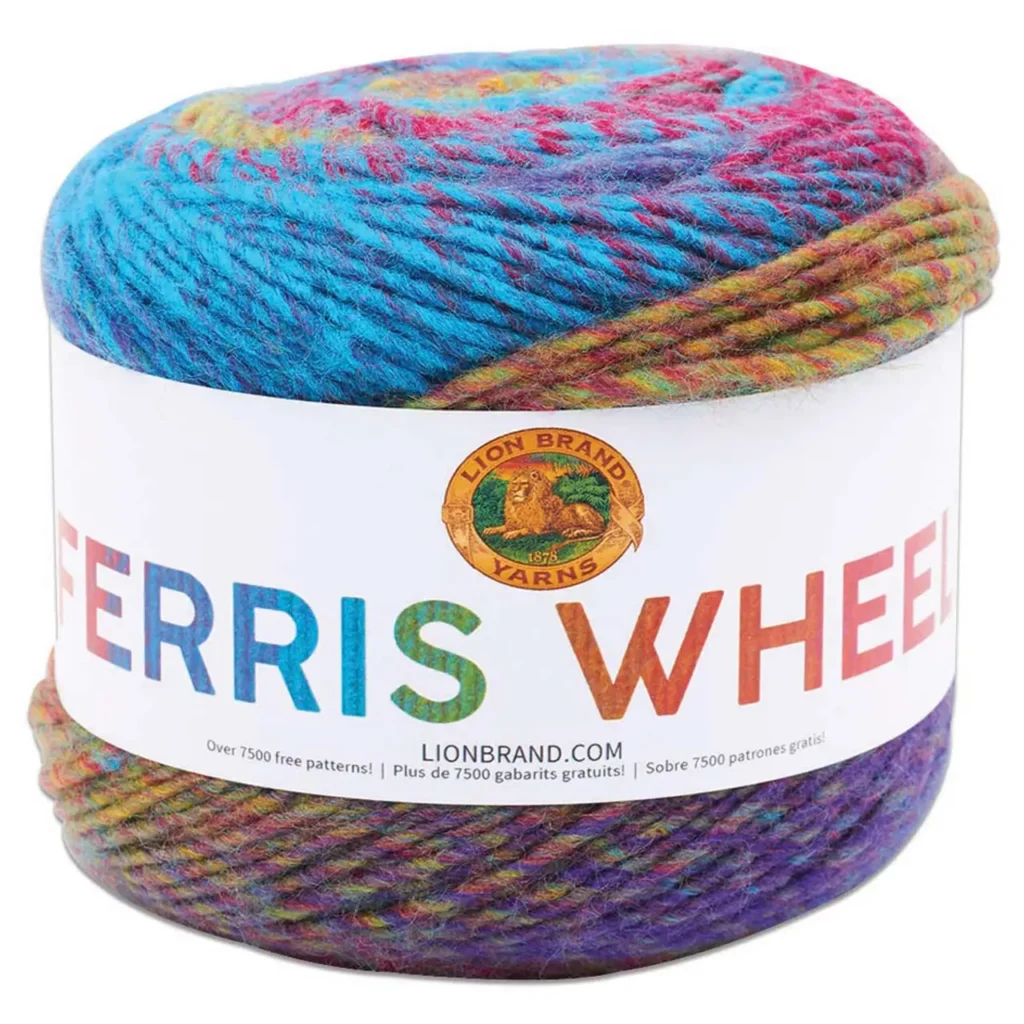 A large skein of Lion Brand Yarns labeled "Ferris Wheel" features a vibrant multicolored pattern with shades of blue, pink, green, and purple. Perfect for joining the Marly Bird Turkey Trot make-along during the annual event, with access to over 7500 free patterns in multiple languages. -Marly Bird