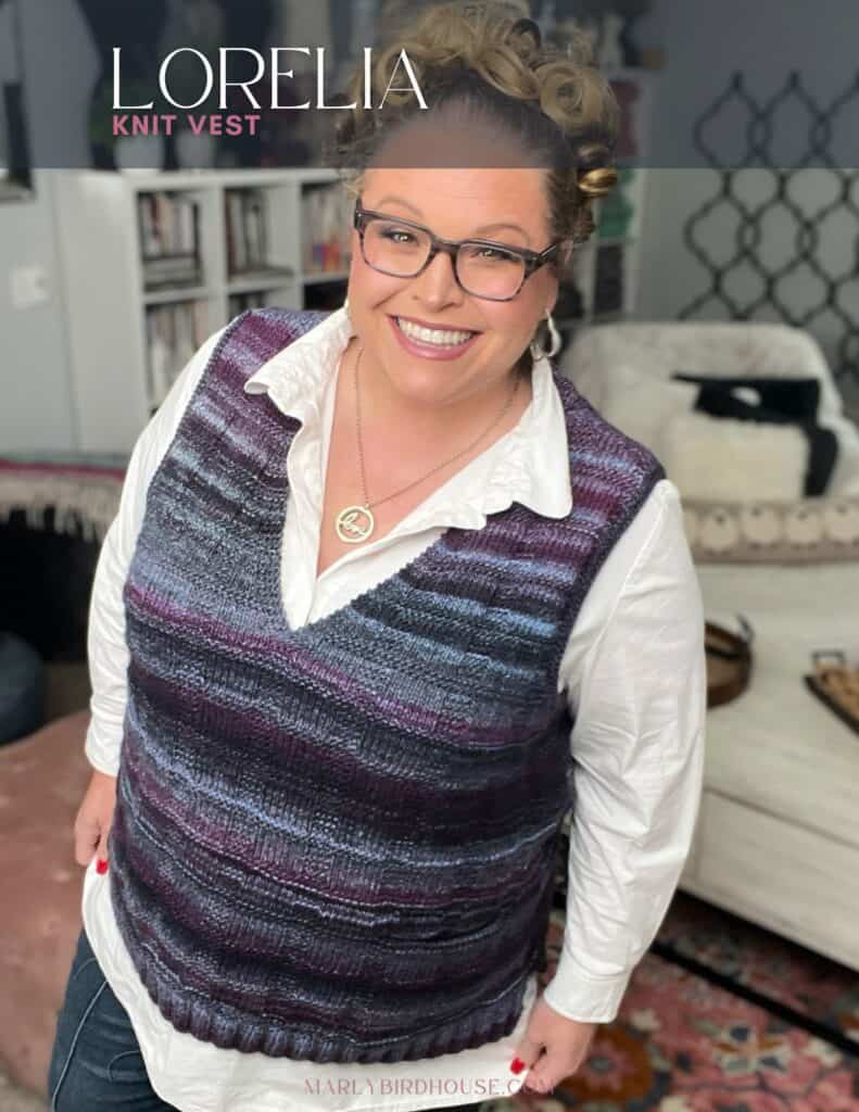 A person smiles while wearing a knit vest over a white shirt. The vest features shades of purple and blue. In the background, there is a couch with a pillow and a shelf with books. The image has text that says "Lorelia Knit Vest. -Marly Bird