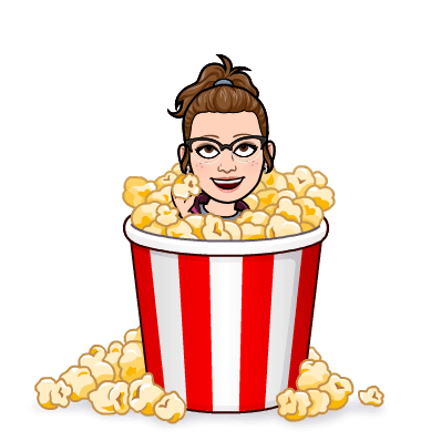 A cheerful cartoon of a person with glasses and brown hair in a ponytail, sitting in a large, red-and-white striped popcorn bucket. Popcorn spills over as they enjoy announcements of Knit and Crochet Giveaways, adding an extra layer of excitement to their day. -Marly Bird