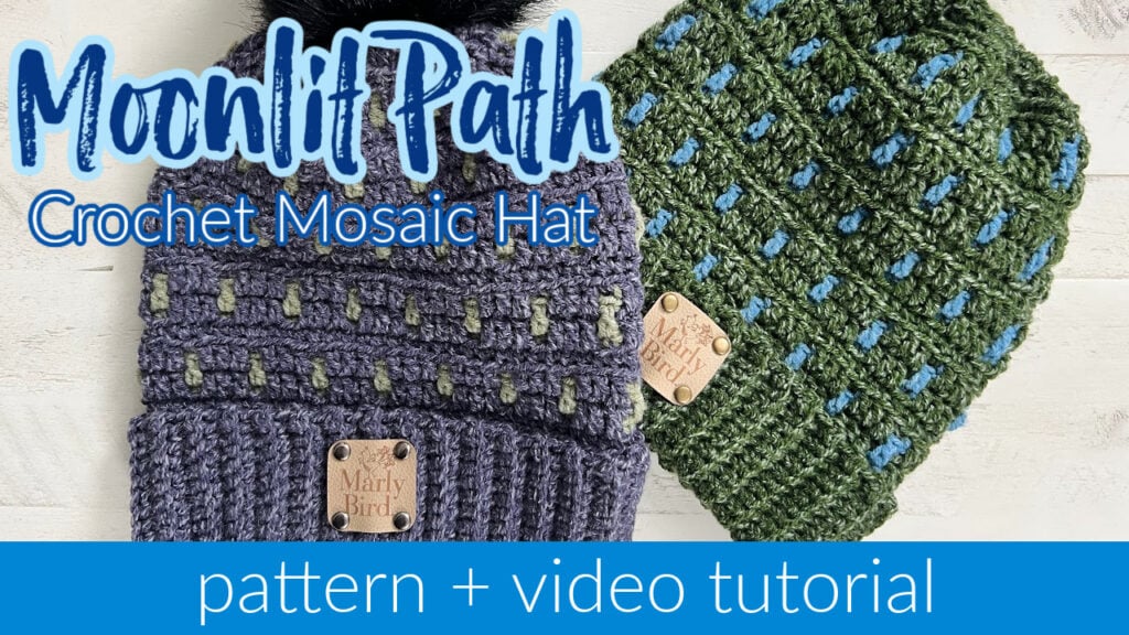 Two textured crochet hats with geometric patterns in green, blue, and gray are displayed on a white background. Each hat features a small "Marly Bird" tag. Text overlay reads "Moonlit Path Mosaic Crochet Hat" with "pattern + video tutorial" below. Perfect for those cozy moments in your favorite slippers. -Marly Bird