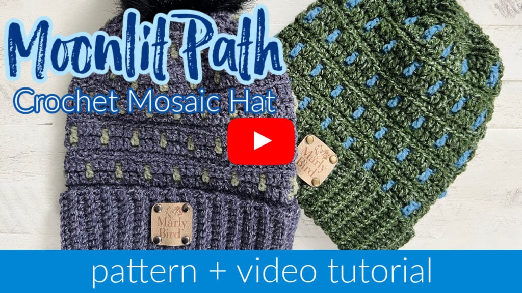 Two crocheted mosaic hats, one gray with green and blue details, the other green with blue details, are displayed. A YouTube play button is centered. Text reads: "Moonlit Path Crochet Mosaic Hat" and "pattern + video tutorial" showcasing a textured design for a unique hat pattern. -Marly Bird