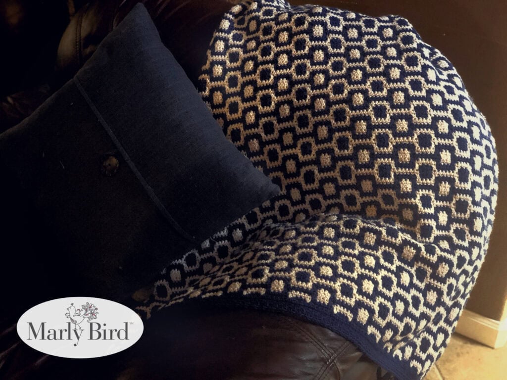 Navy and white mosaic crochet baby blanket on leather couch showing finished border