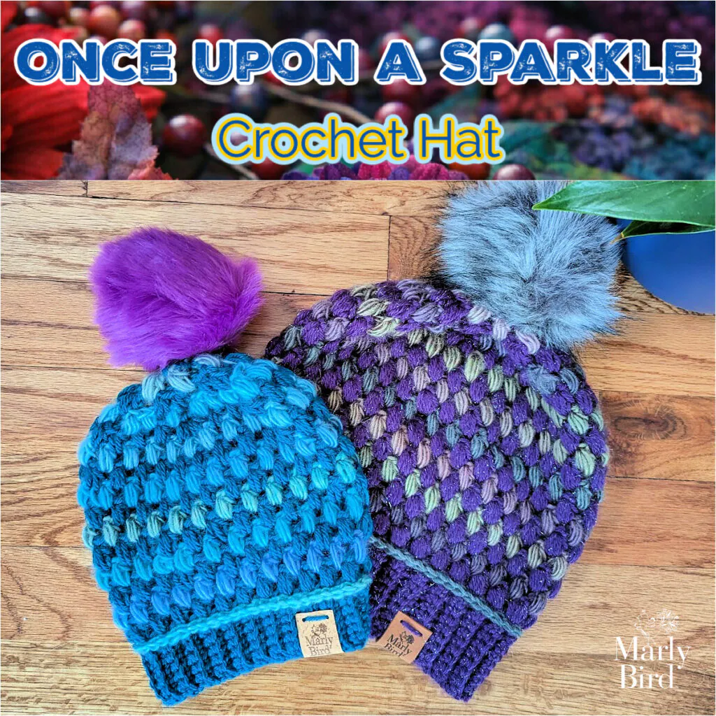 Two crochet hats with puff stitch texture, one blue with purple pom-pom, one purple with gray pom-pom, on wood surface.