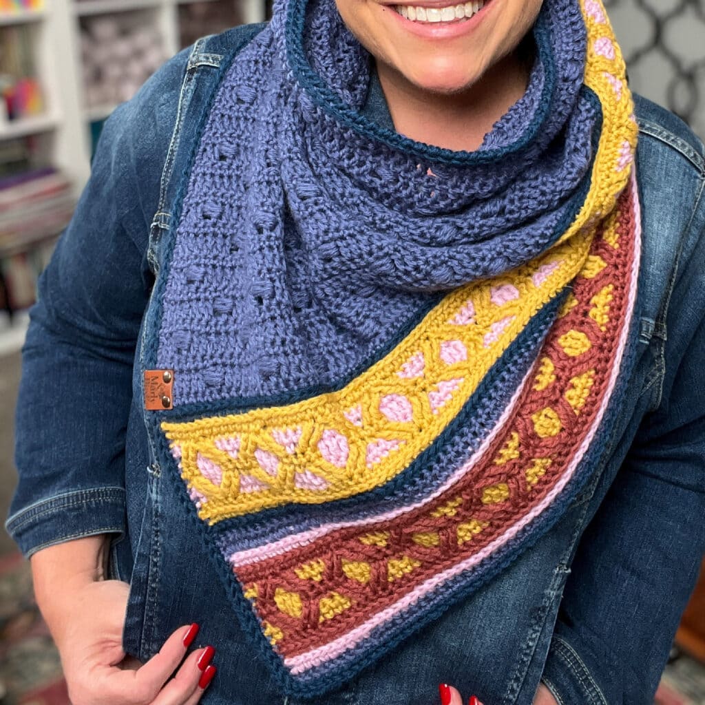 Colorful knit scarf with blue, yellow, pink, and burgundy sections; features distinct textured stitch patterns.