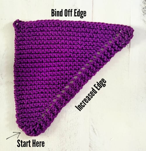 Purple triangular knitted swatch with clear stitch definition, showing start point, increased edge, and bind-off edge.