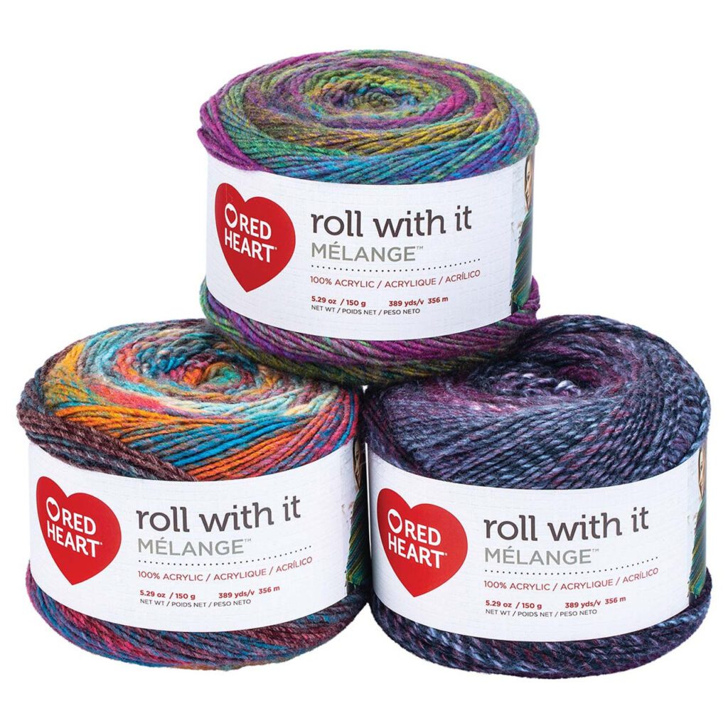 Three skeins of Red Heart "Roll With It Mélange" yarn are stacked, ready for your next Marly Bird Make-Along. The multi-colored yarn, perfect for a Turkey Trot project, is labeled with the brand name and product details like fiber content and weight. -Marly Bird