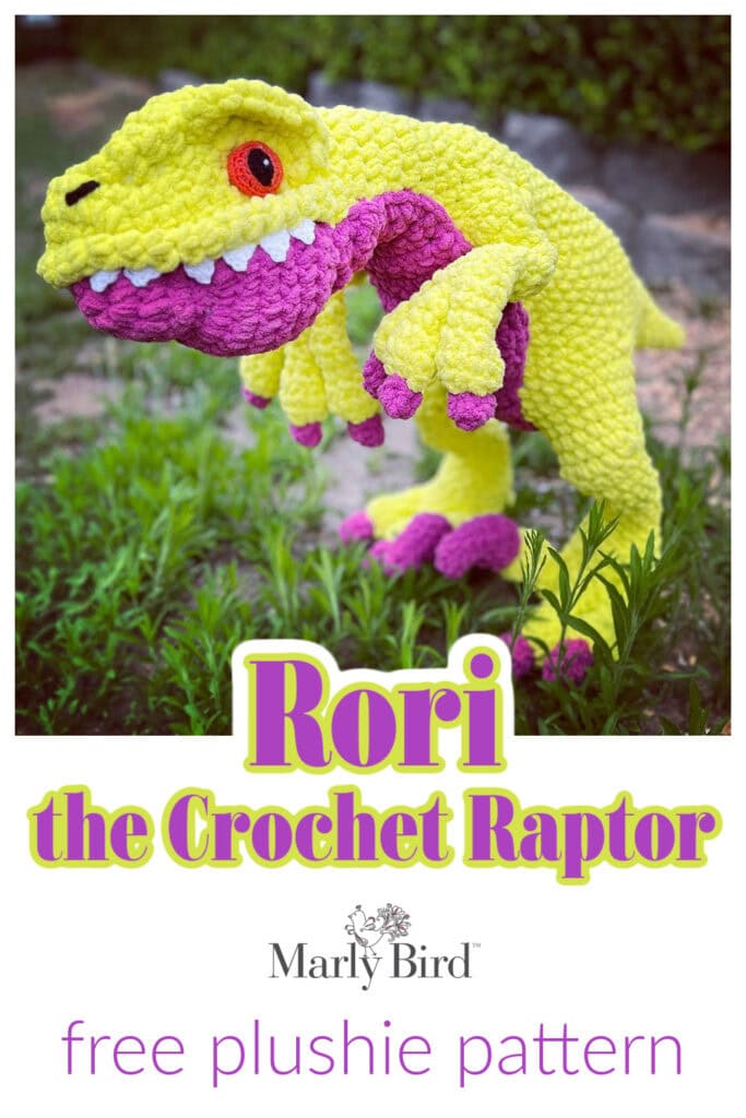 Colorful crocheted dinosaur standing on grass. The text reads: "Rori the Crochet Raptor" and "Marly Bird free Dinosaur Plush pattern. -Marly Bird